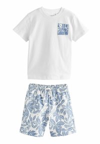 Tricou alb din bumbac cu un buzunar cu model albastru, asociat cu șorturi cu model de frunze albastre și albe, dotate cu o talie elastică.