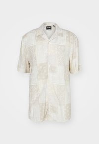 Kortærmet skjorte i lys beige med paisley- og polkaprikker. Lavet af letvægtsstof med en afslappet krave og knaplukning foran.