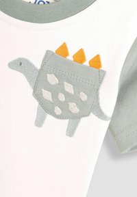 Kurzärmliges weißes Hemd mit einem hellgrünen Kragen, ausgestattet mit einer gestickten grauen Dinosaurier-Tasche mit orangefarbenen Stacheln und weißen ovalen Mustern.