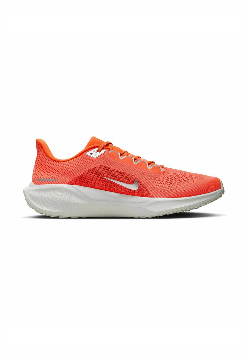 Baskets de course Nike lumineuses orange avec semelle blanche, tige en mesh et logo swoosh argenté sur fond blanc.