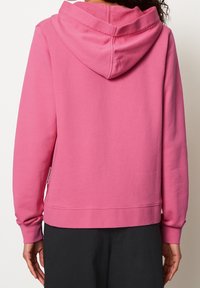 Hoodie in felroze, met een zachte textuur, geribde boorden en een label aan de onderzijde. Glad materiaal en een casual pasvorm.