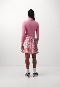 Top ajustado de manga larga rosa combinado con una falda acampanada floral que presenta patrones en rosa y verde, terminando con un dobladillo con volantes.
