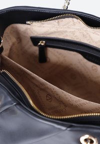 Svart läderhandväska med dragkedjestängning. Inuti finns en beige tygfoder med logomönster och en extra blixtlåsficka. Guldiga detaljer.