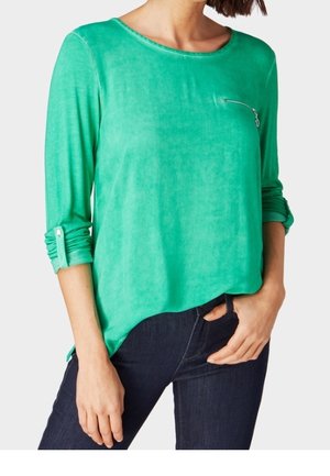 Groen langarmig shirt met een ronde hals en een borstzak met rits. Heeft opgerolde manchetten en een ontspannen pasvorm in een glad, zacht stof.