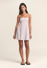 Hele lilla triibuline kleit, millel on keha järgnev ülaosa, spagetirihmad ja lehvikukujuline seelik. Sobitatud beežide varbavahekingadega. Siidine puuvillane tekstuur.