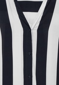 Navy- und weiße, vertikal gestreifte Bluse mit V-Ausschnitt, durchgehender Knopfleiste und subtilen Steppdetails. Weicher, leichter Stoff.