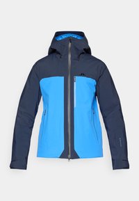 Vízhatlan dzseki, kék felsőrésszel és sötét navy ujjakkal. Elöl cipzárral, állítható kapucnival és egy mellzsebbel rendelkezik.