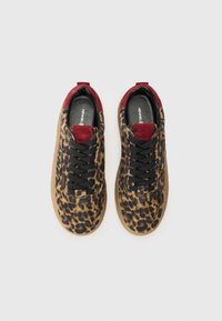 Baskets à imprimé léopard avec un design à lacets noir, des accents en suede rouge au niveau du col et une semelle en caoutchouc marron, présentant une texture lisse.