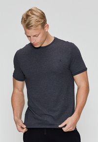 Mørk grå kortærmet t-shirt i bomuldsblanding med round neckline og et diskret logo på brystet. Blød tekstur med tætsiddende pasform.