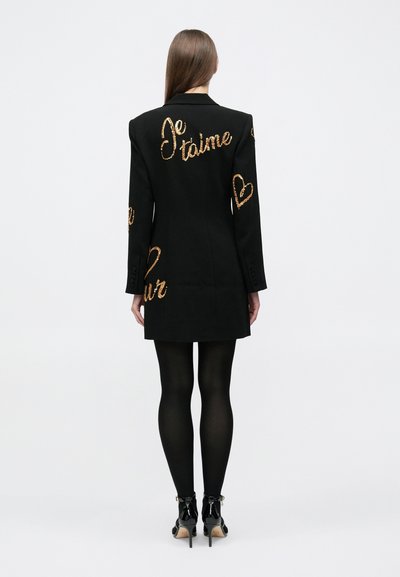 Sacou negru cu mâneci lungi, cu fraze și inimi brodate în aur pe spate. Croială ajustată și textură fină.