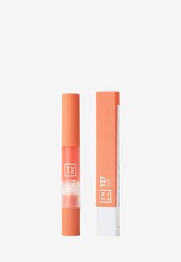 Gloss à lèvres corail dans un tube transparent avec un capuchon assorti, accompagné d'une boîte orange texturée étiquetée avec les informations sur le produit.