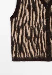 Gilet en maille duveteuse avec motif zèbre marron et beige et boutons noirs sur le devant.