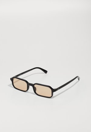 Óculos de sol retangulares pretos com lentes castanhas claras, apresentando uma armação grossa, forma angular e um discreto detalhe em dourado nas hastes.