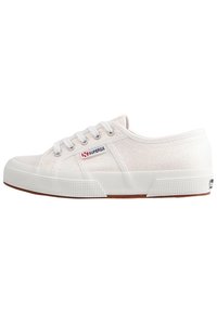 Baskets en toile blanches avec une surface texturée, semelle en caoutchouc blanc et accents marron contrastants. Comprend six œillets et un logo sur le côté.