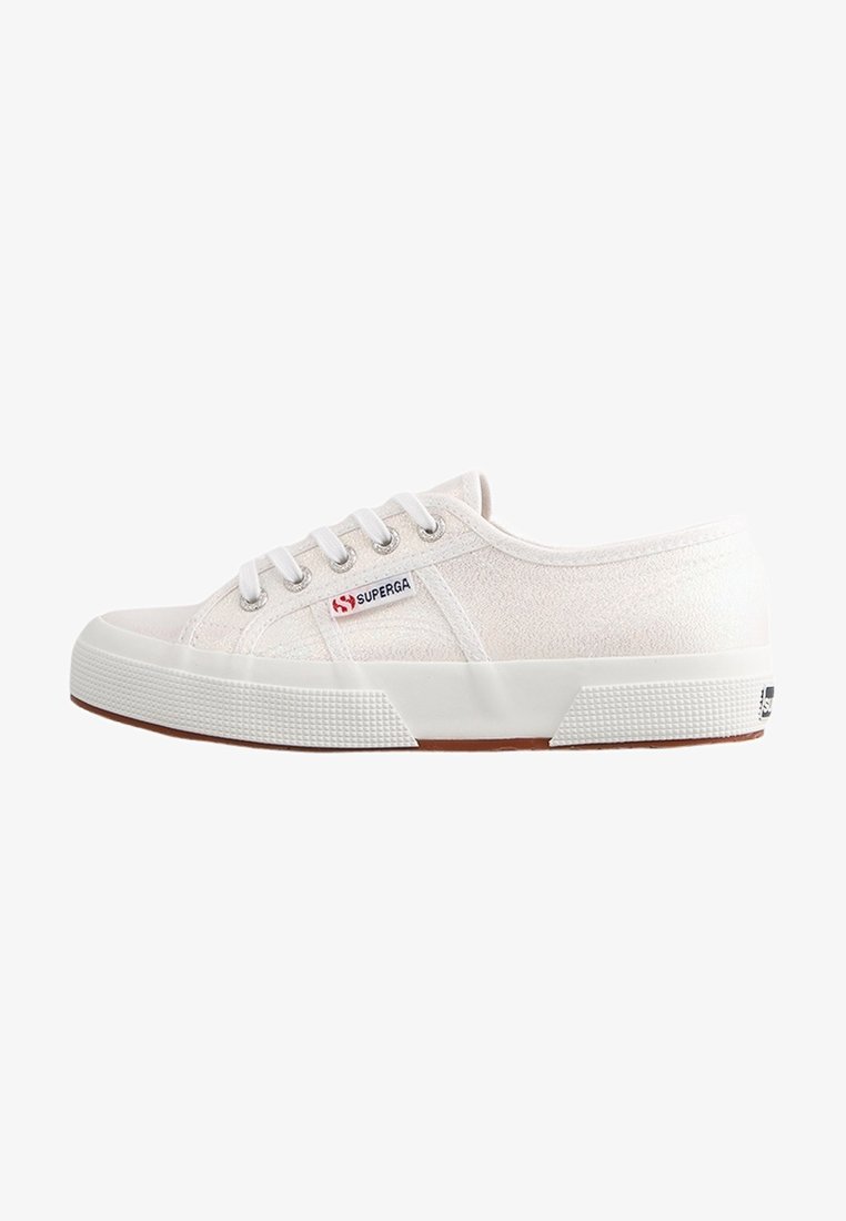 White canvas sneakers with a textured surface, white rubber sole, and contrasting brown accents. Features six eyelets and a side logo.