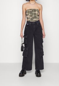 Svarta cargobyxor med vida ben, flera sidofickor och hög midja. Matchas med en grön rutig strapless topp och svarta chunky stövlar.