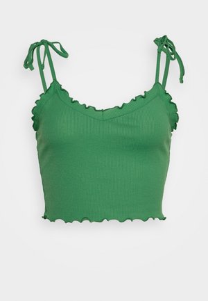 Top corto verde acanalado con bordes rizados, cuenta con tirantes ajustables y un escote en V. Textura suave y diseño ajustado.