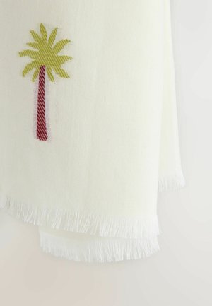 Valge kangas, millel on turritatud servad ja ühe nurgas väike tikandiga palmipuu punase tüve ja roheliste lehtedega.