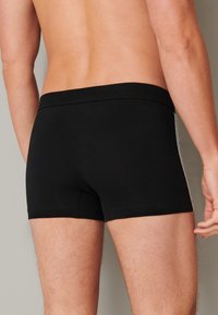 Černé boxerky s fitted designem. Vyrobené z hladkého textilu, s jednobarevným vzhledem a elastickým pasem. Jednoduchý styl.