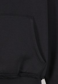 Mustast dressipluusist, millel on pehme kangakate, eesmine tasku ja soonikkoes mansetid. Alumine serv on detailseks efektiks kulunud.