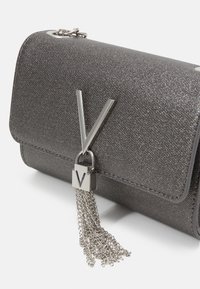 Borsa con texture metallica grigia, caratterizzata da una chiusura e dettagli a nappina in argento, con un logo "V" argentato ben visibile sulla parte anteriore.