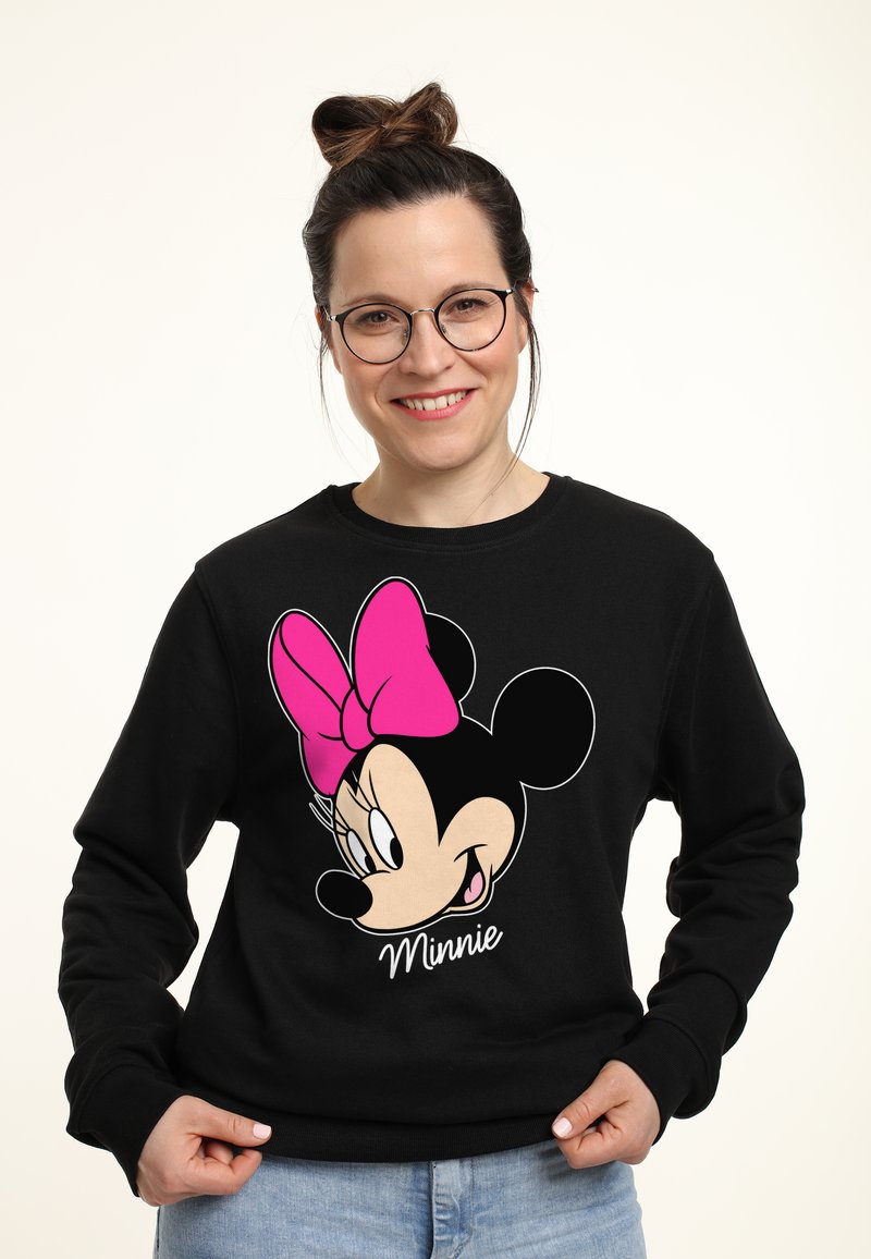 Felpa nera con una grafica colorata di Minnie Mouse, con un fiocco rosa e il nome "Minnie" stampato sotto. Tessuto morbido, vestibilità casual.
