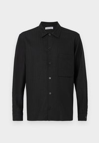 Svart langermet skjorte med knapper og vertikale striper, brystlomme på venstre side, og klassisk krage.