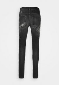 Jeans ajustados negros con un acabado desgastado, que cuentan con dos bolsillos traseros y una apariencia texturizada, fabricados en tela de denim.