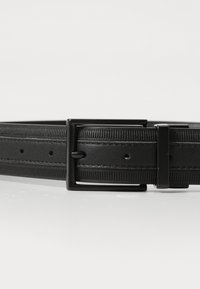 Schwarzer Leder-Gürtel mit strukturierter Oberfläche, ausgestattet mit einer rechteckigen schwarzen Metallschnalle und mehreren Einstelllöchern entlang des Riemens.