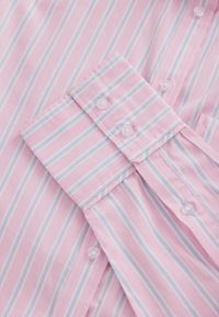 Lyserød skjorte med tynde blå striber, der har en spids krave, manchet og hvide knapper. Glat stoftekstur.