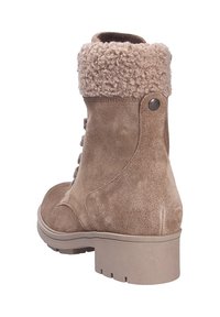 Bottine en suède tan avec un poignet flou beige, bout rond et une semelle en caoutchouc robuste. Présente des coutures discrètes et des accents métalliques.