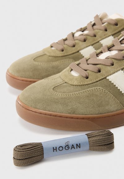 Beige suède sneakers met bruine veters en gumzolen, vergezeld van een aparte set bruine veters, gelabeld als Hogan.