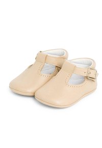 Scarpe in pelle beige con punta rotonda, design a t-strap, fibbia laterale e dettagli perforati lungo il bordo superiore. Rivestimento interno morbido.