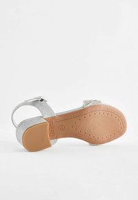 Zilveren glitter sandalen met een gemarmerde zool, verstelbare enkelband en een ronde neus. Duurzame rubberen buitenzool met een reliëf sterrenpatroon.