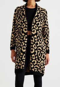 Lång kofta i stickad tyg med svart bakgrund och beige leopardmönster. Öppen fram, långa ärmar och ribbade ärmslut.