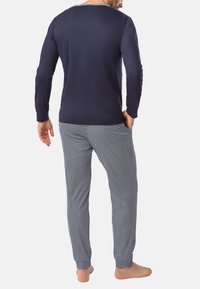 Navy langemouwen top gecombineerd met gestreepte broek met blauw en witte diamantvormen, gemaakt van zacht materiaal.