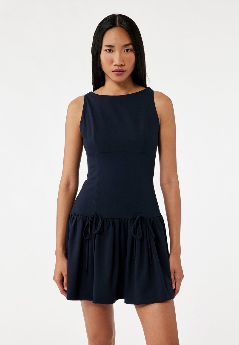 Navy blue sleeveless dress with a fitted bodice, flared skirt, and adjustable drawstring accents at the waist for a custom fit. Smooth texture.