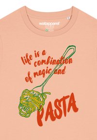 Perzikkleurig t-shirt met groene en oranje tekst en een illustratie van een vork die gele pasta vasthoudt, met een speelse uitspraak over het leven.