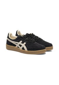 Black suede sneakers with cream accents, round toe, flat rubber sole, and black laces. Designed with side stripes and textured details.