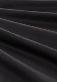 El tejido negro presenta una textura suave con pliegues superpuestos, enfatizando un ligero brillo y una apariencia uniforme en todo su conjunto.