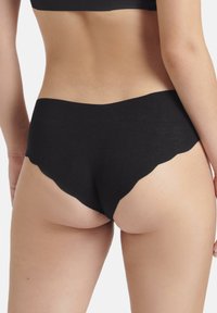 Schwarze Baumwoll-Hipster mit gewelltem Rand, die eine glatte Textur und einen low-rise Schnitt aufweisen, entworfen für Komfort und minimale Sichtbarkeit.