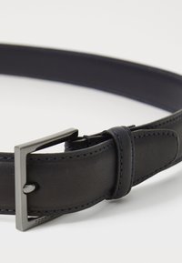 Ceinture en cuir noir avec une texture lisse, dotée d'une boucle en métal carrée et d'accents de couture bleu foncé. Design compact et élégant.
