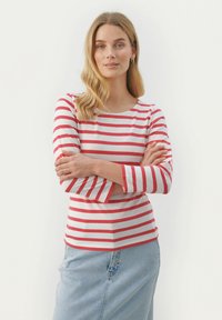 Punane ja valge triibuline pika varrukaga särk ümmarguse kaelusega, millele on sobitatud helesinine denim-seelik, millel on mugav lõige ja kumer äär.