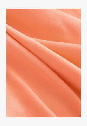 Persikka värvi kangas sileda tekstuuriga, millel on pehmed, langevad voldid, mis rõhutavad selle kerget ja venivust.