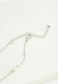 Una collana in argento con piccoli accenti di perle rotonde, dotata di chiusura a moschettone e di una lunghezza regolabile con anelli circolari.
