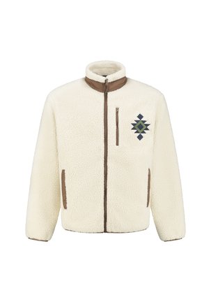 Veste en polaire couleur crème avec un col haut, des accents marron, une fermeture éclair intégrale et des broderies géométriques en vert et bleu marine sur la poitrine.