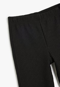 Sorte ribbede tights med en tekstureret overflade og elastisk talje, med lodrette ribbede detaljer og et strømlinet design.