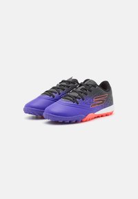 Chaussures de sport violettes et noires avec un design texturé, des accents orange contrastants et une semelle en caoutchouc durable. Présentent des lacets noirs.