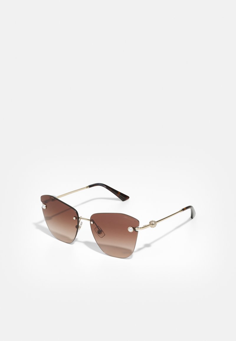 Occhiali da sole con gradiente marrone, lenti geometriche oversize, montatura in metallo dorato e dettagli decorativi in perle sugli occhiali.