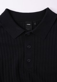 Μαύρο ριγωτό πόλο μπλουζάκι με διπλωμένο γιακά, τρία κουμπιά και ετικέτα με την επιγραφή "FORMER" στο μέγεθος L. Μαλακή υφή πλεκτού.